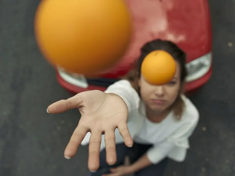 Девушка бросает два апельсина